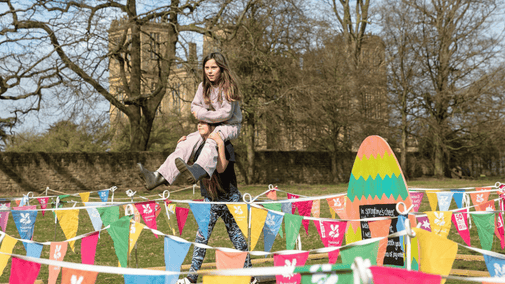 Sister carrying her sister through the bunting maze on her shoulders at Hardwick.